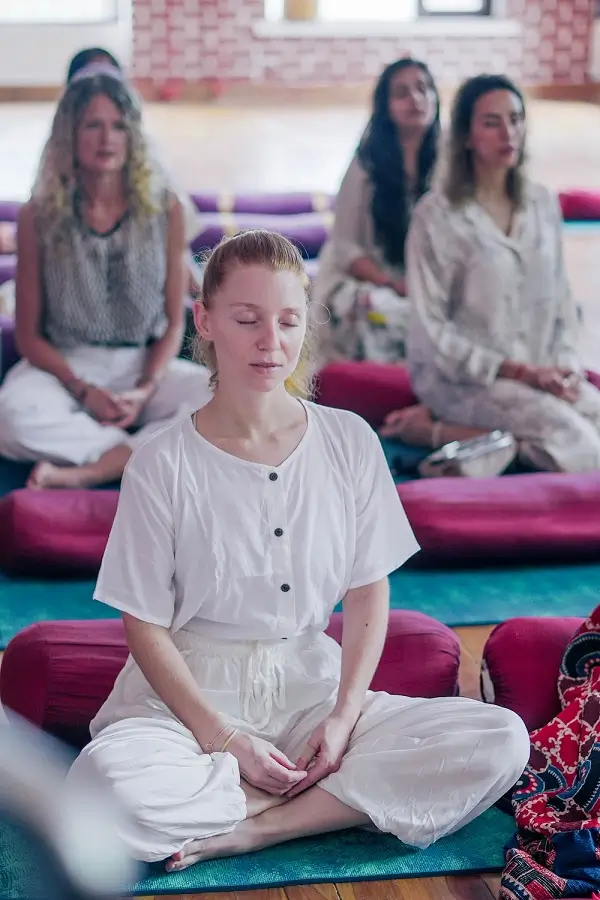 Students sitting in meditation with marigold garlands during a philosophy session