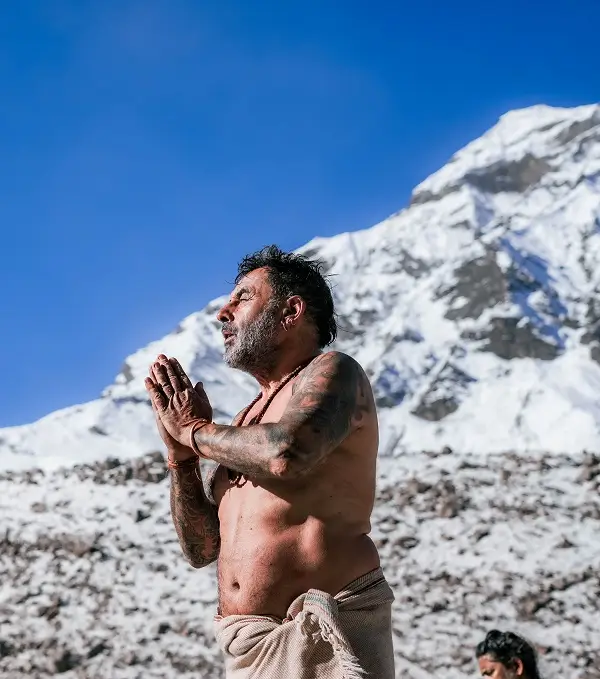 A pilgrim in prayer beneath a snow-covered peak