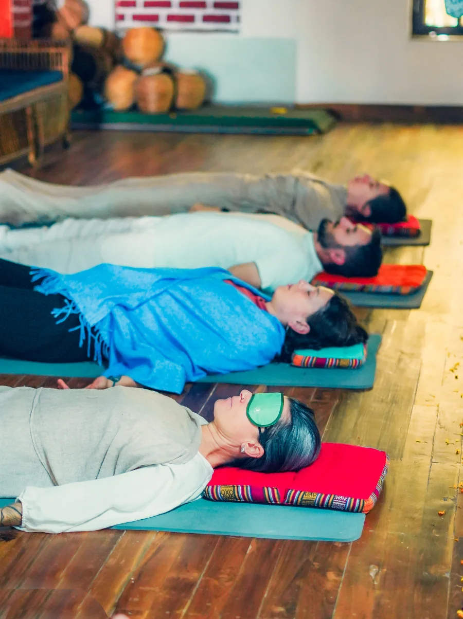 Students lying in a row on mats during a guided Yoga Nidra session