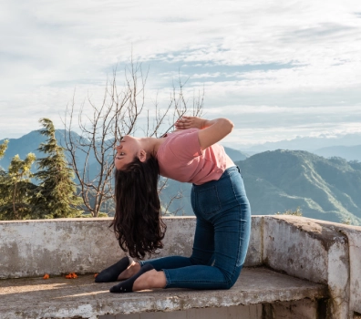 A student in camel pose on a hilltop terrace