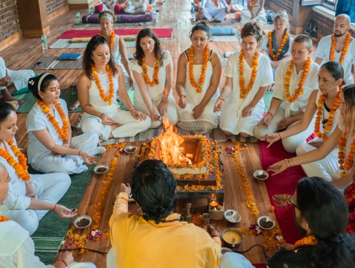 Students in white seated around a fire ceremony at World Peace Yoga School