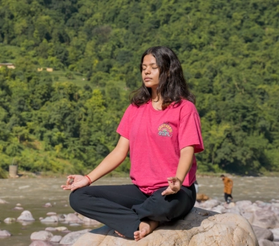 A student meditating on a rock beside the Ganga