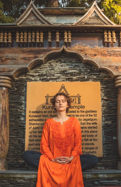 A student meditating in front of the Kunjapuri Temple plaque