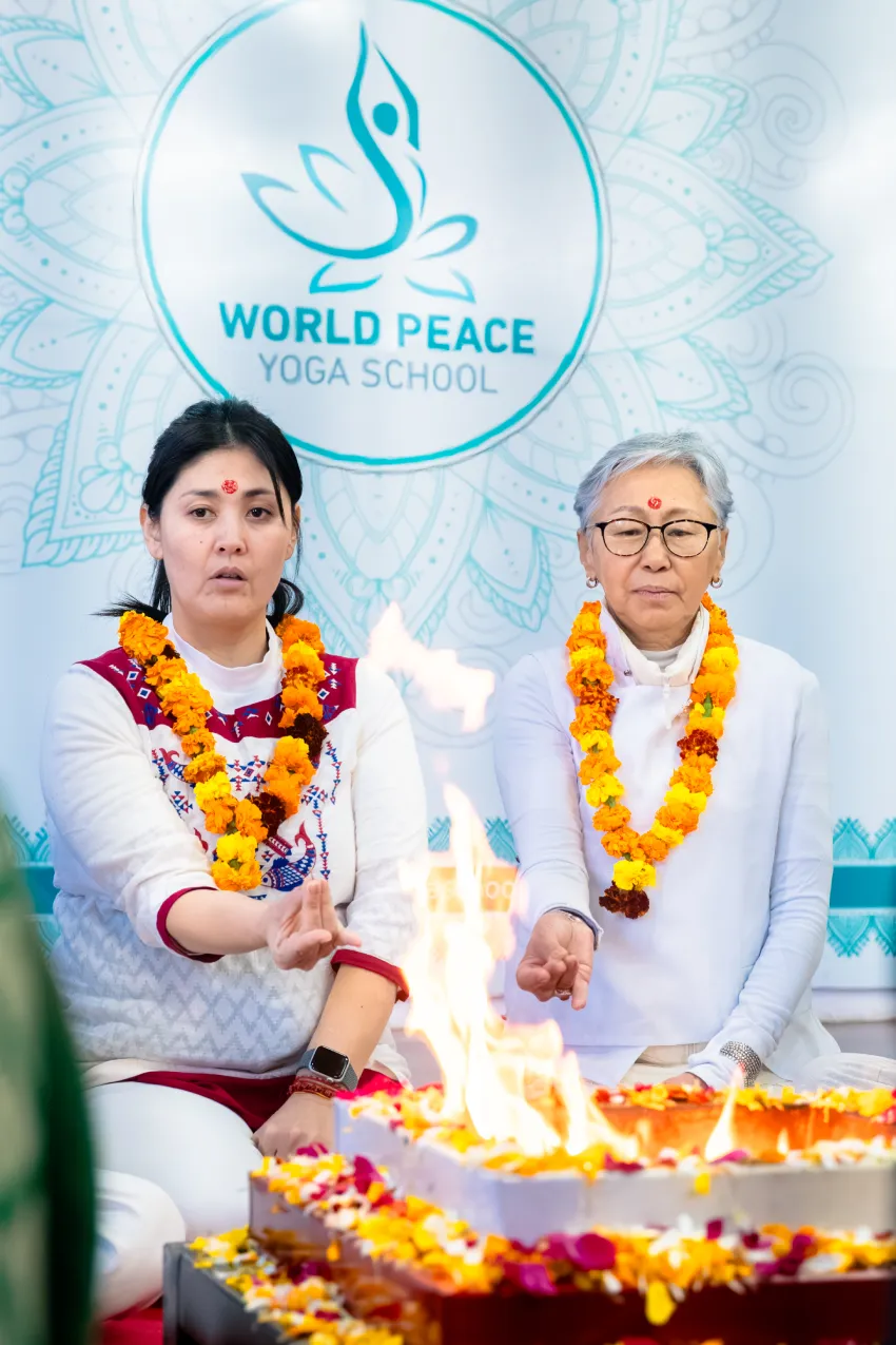 Two students with marigold garlands offering to the sacred fire at World Peace Yoga School