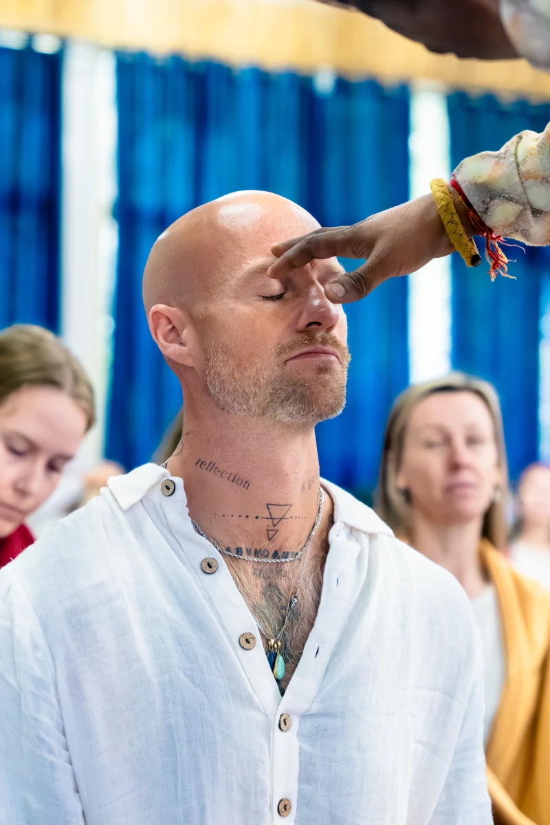 A teacher touching a student's third eye during a Shakti initiation