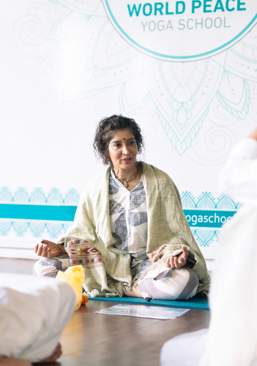 A teacher leading a seated philosophy session at World Peace Yoga School