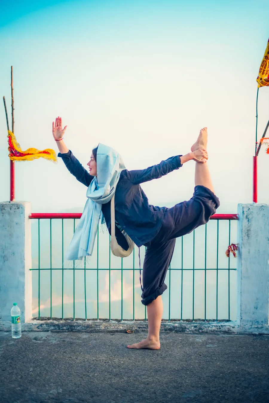 A student in dancer pose on a hilltop temple terrace above Rishikesh