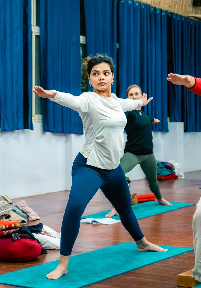 Students holding warrior two pose in the yoga hall