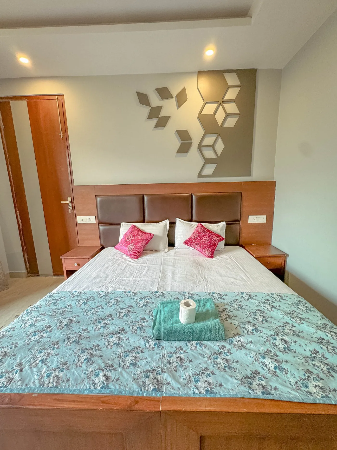 Double room with a turquoise bedspread and pink cushions
