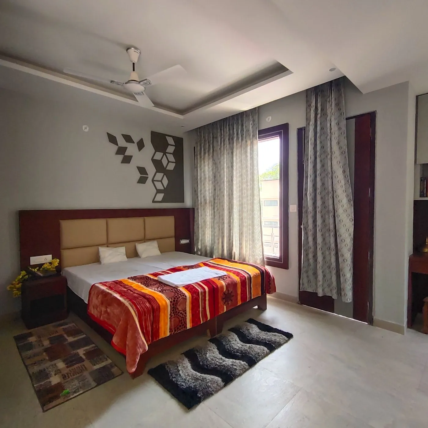 Double room with a striped bedspread and patterned rugs