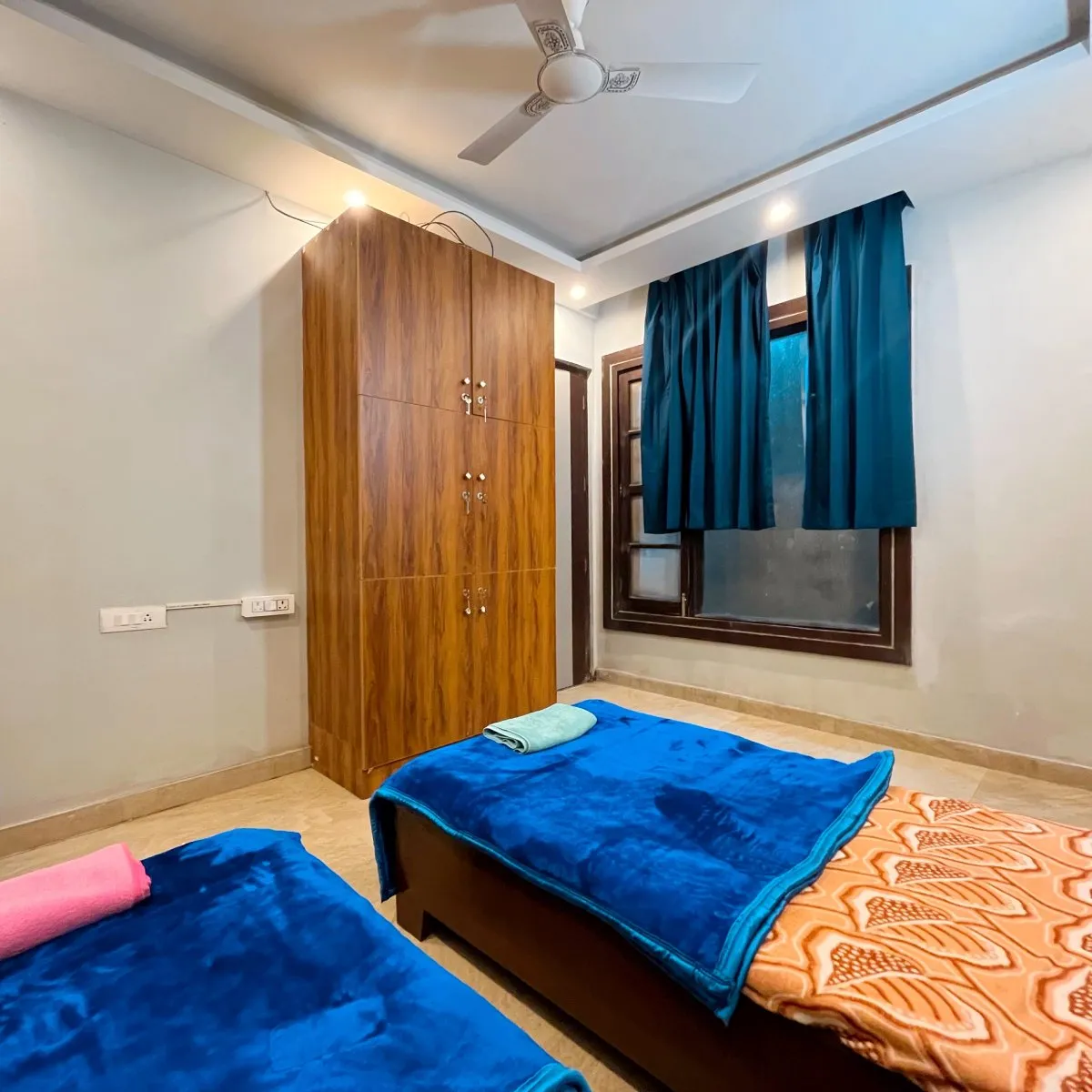 Twin room with blue blankets and a wooden wardrobe