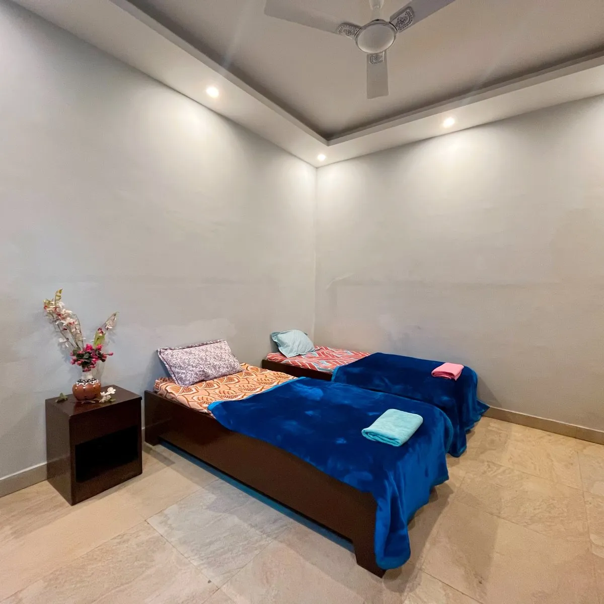 Twin room with blue blankets beside a flower vase