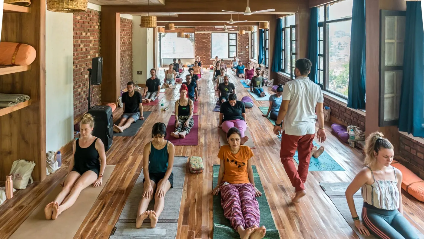 Students practising in the wooden-floored yoga hall