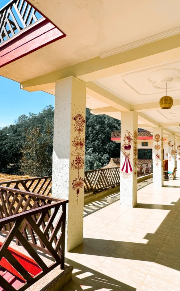 A sunlit veranda with painted pillars overlooking green hills