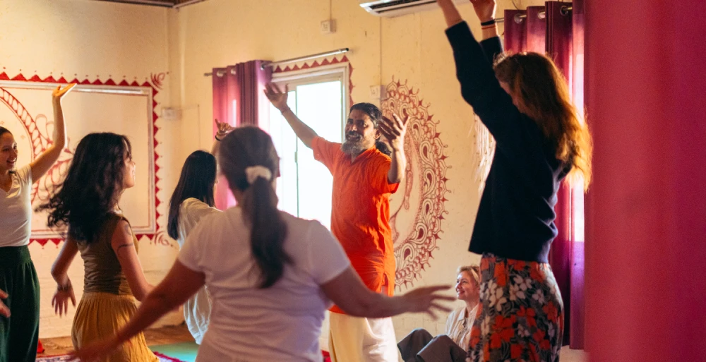 A teacher leading a joyful movement class in a painted yoga hall