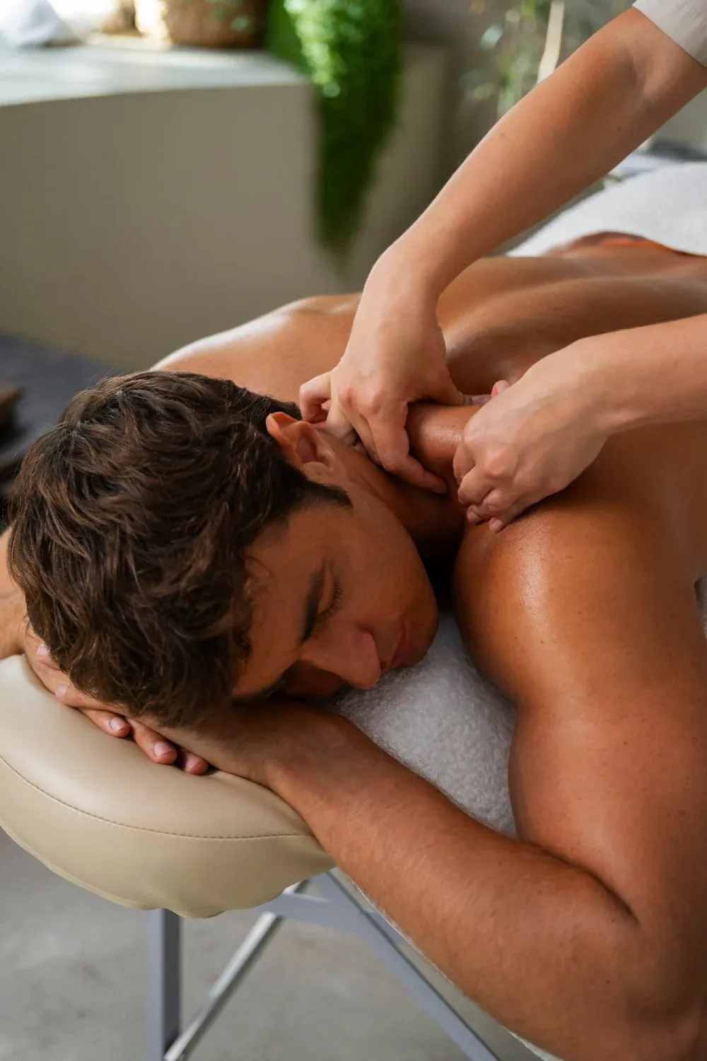 A therapist massaging a man’s shoulders on a massage table