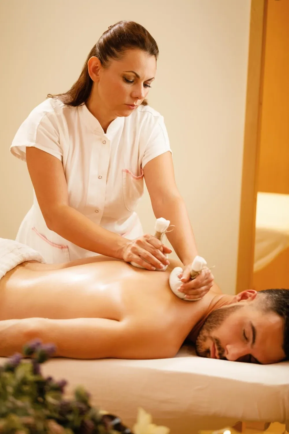 A therapist giving a herbal poultice massage