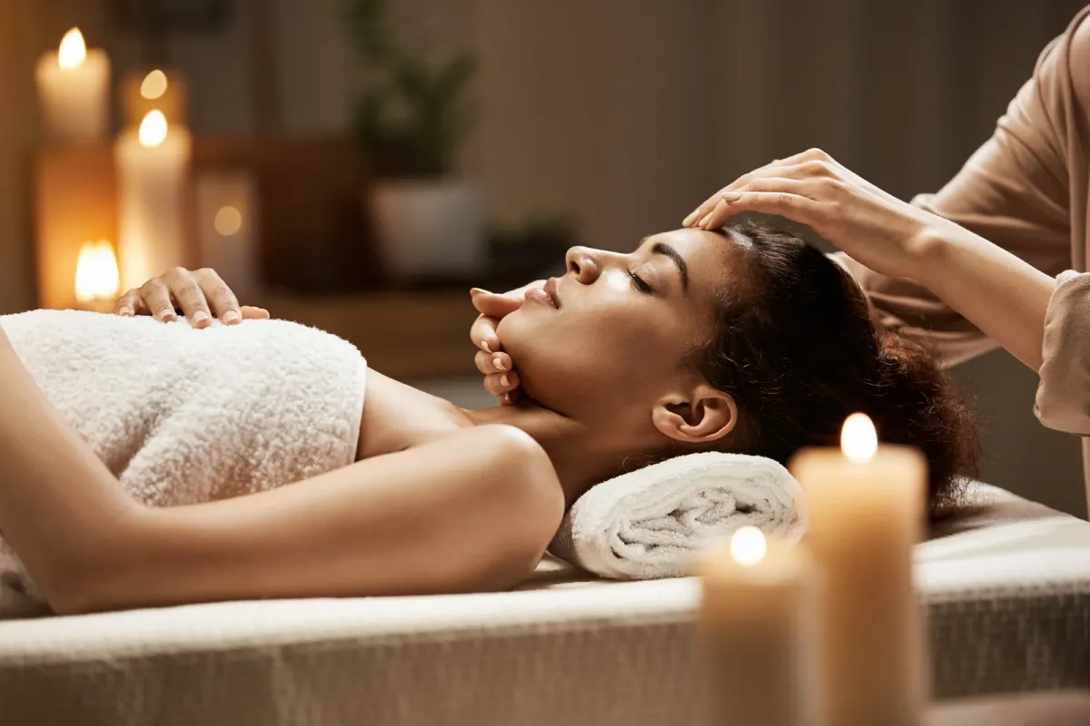 A woman receiving a face and head massage by candlelight
