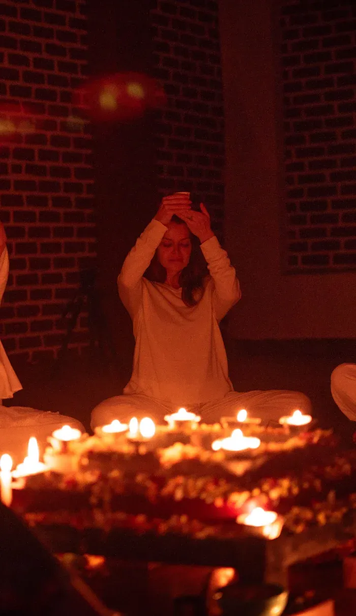 A participant raising a cup of cacao in a candlelit circle