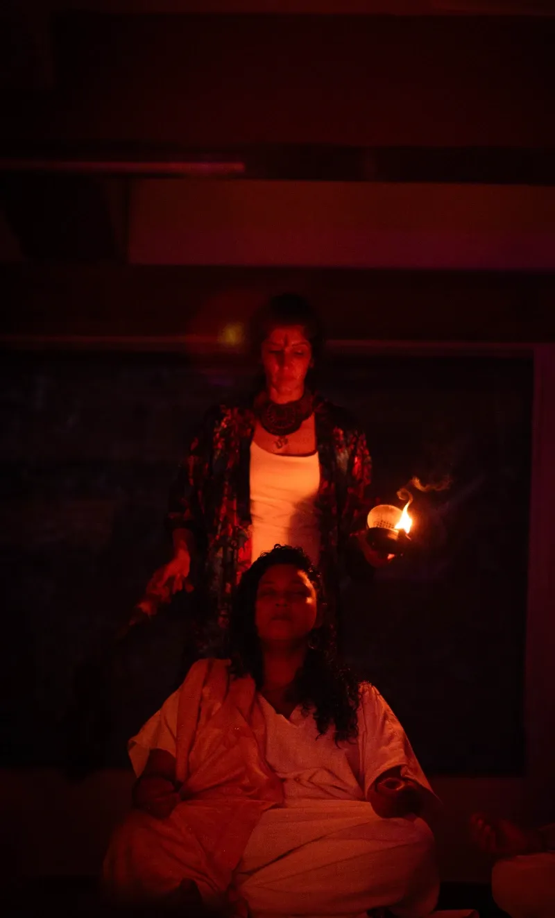 A facilitator holding a candle above a seated participant
