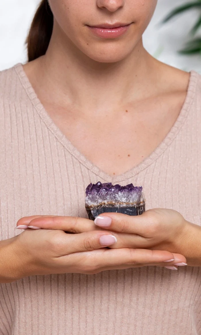 A woman resting an amethyst on her stacked hands
