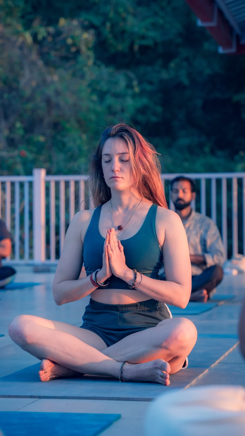 A woman meditating with palms joined during a rooftop class