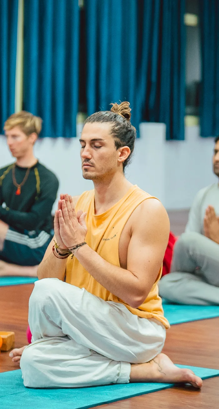 A man meditating with palms joined during a group workshop