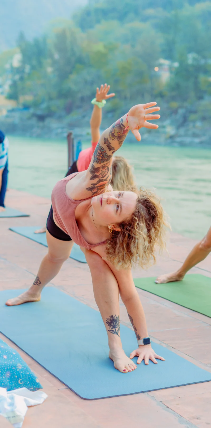 A woman in triangle pose during a riverside yoga class