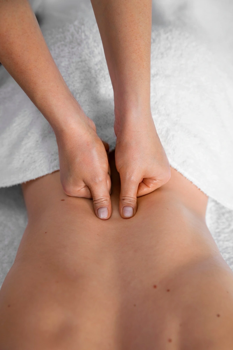 A therapist pressing both thumbs into a guest’s lower back