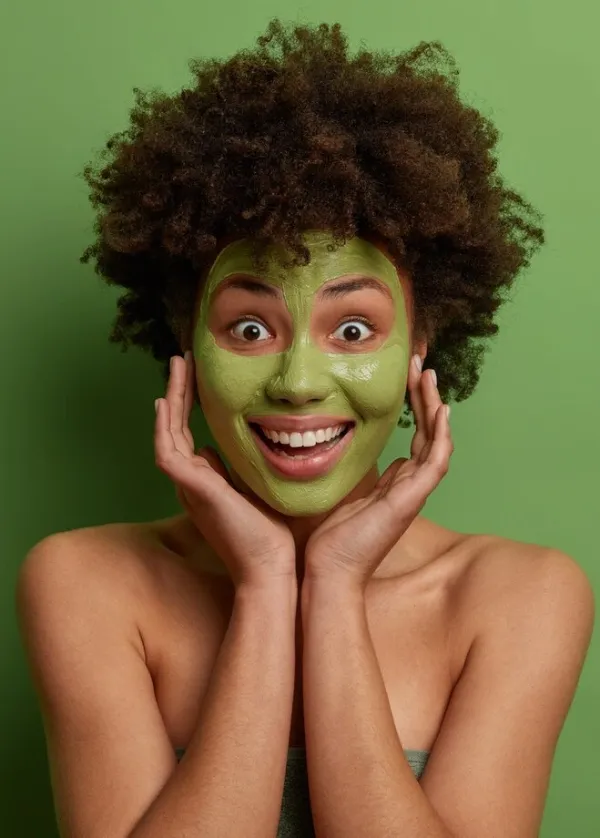 A delighted woman wearing a green herbal face mask