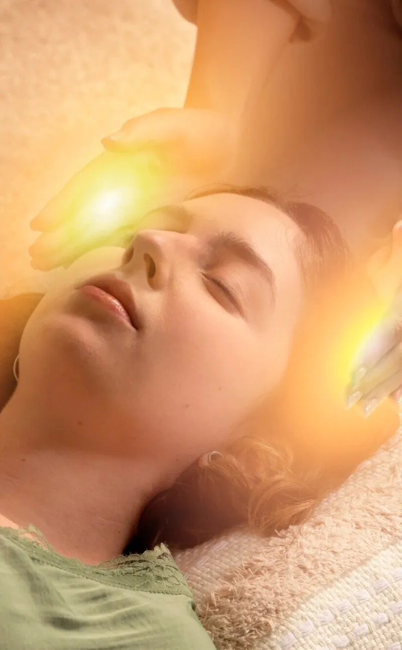 Glowing hands above a woman&rsquo;s face during an energy healing