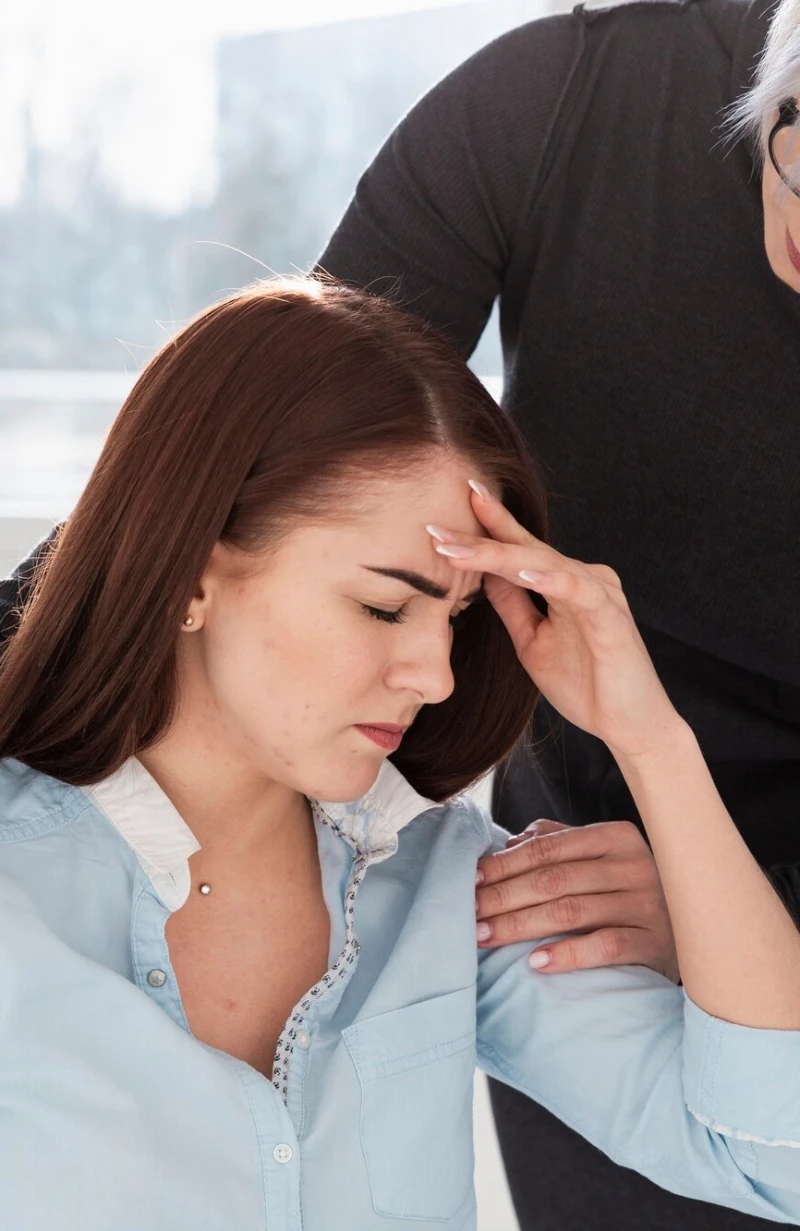 A healer resting a comforting hand on a distressed woman&rsquo;s shoulder