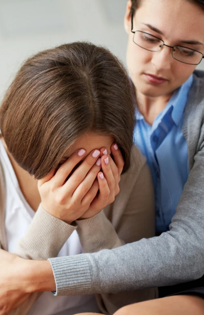 A healer embracing a woman who is crying into her hands