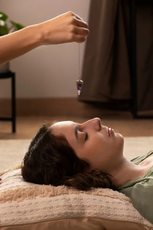 A pendulum swinging above a resting woman’s face