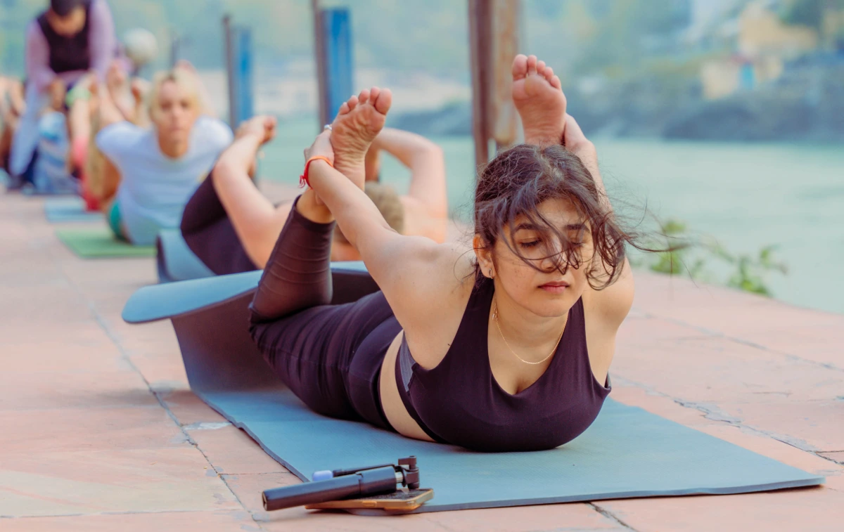 A student in bow pose during a riverside yoga class