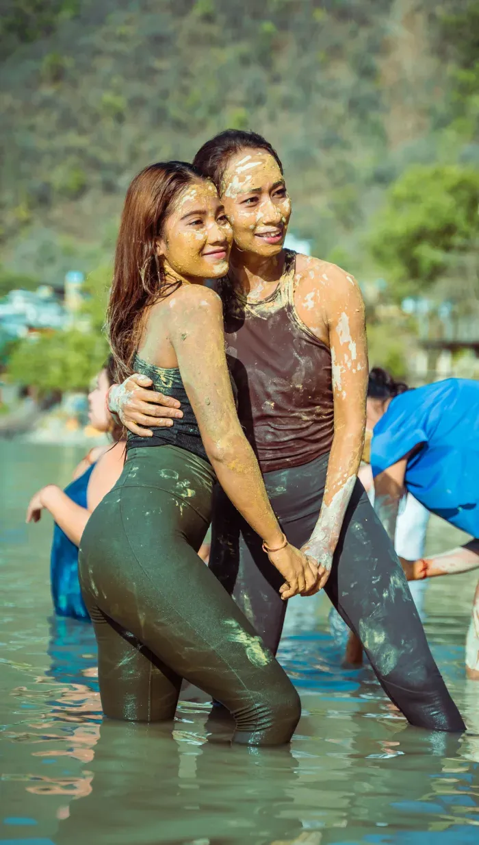 Two friends laughing together in the Ganges after a mud bath