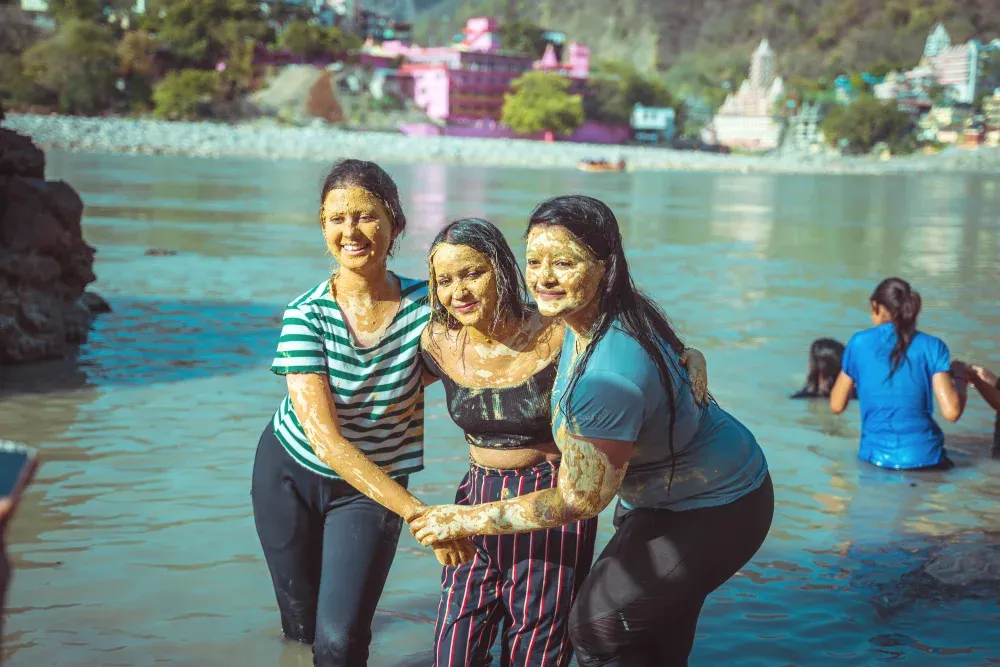 Friends covered in mud laughing together in the Ganges
