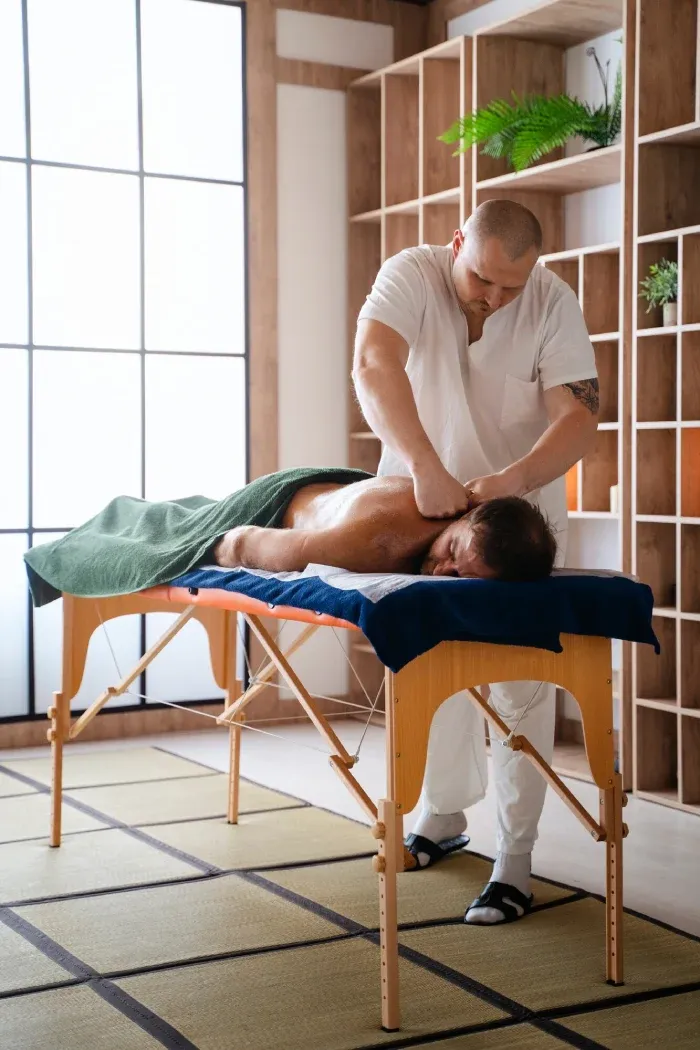 A therapist giving a back massage in a bright treatment room