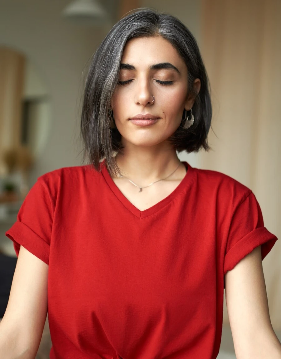 A woman meditating with her eyes closed and a calm expression