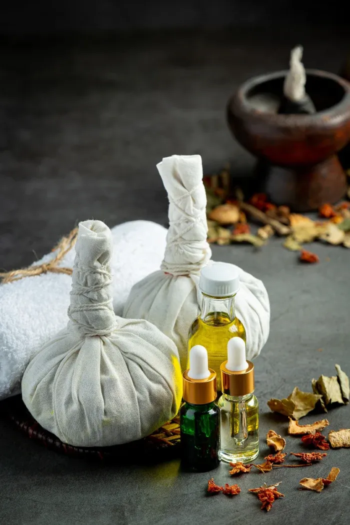 Herbal poultices, oils, and dried herbs laid out for Ayurvedic treatment