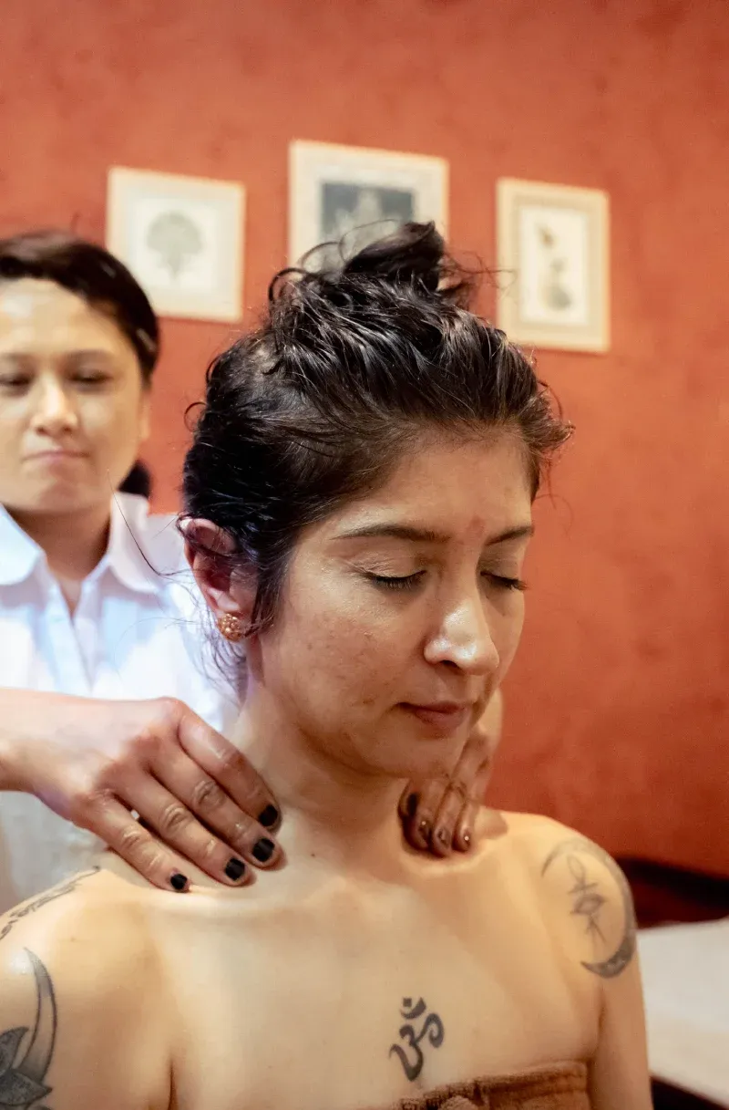 A therapist massaging oil into a woman’s shoulders