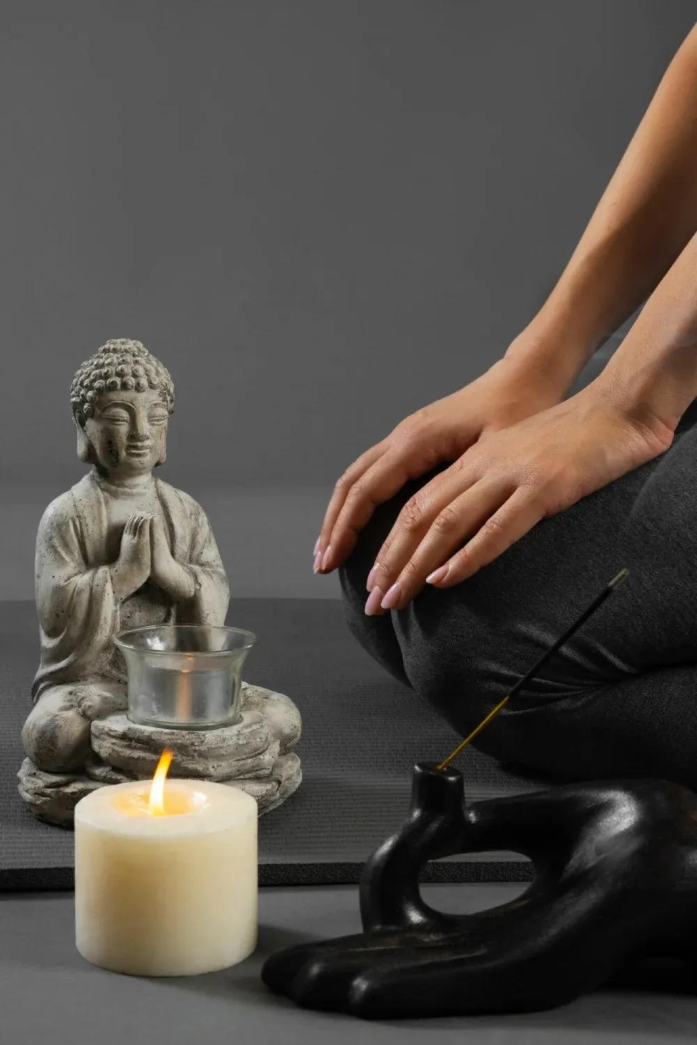 A meditator beside a Buddha statue, a candle and incense