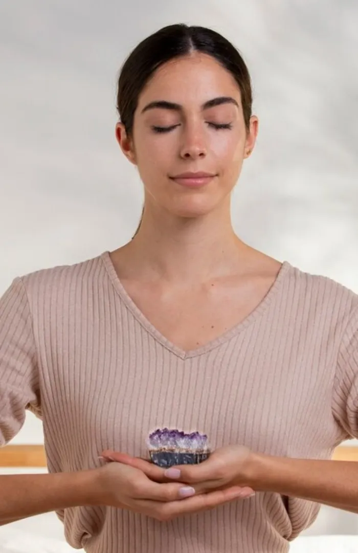 A woman meditating with an amethyst crystal in her hands