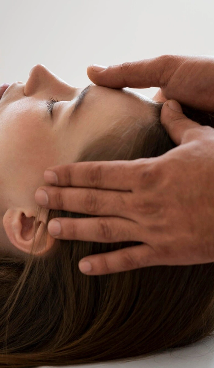 A healer’s hands resting on a woman’s forehead and temple