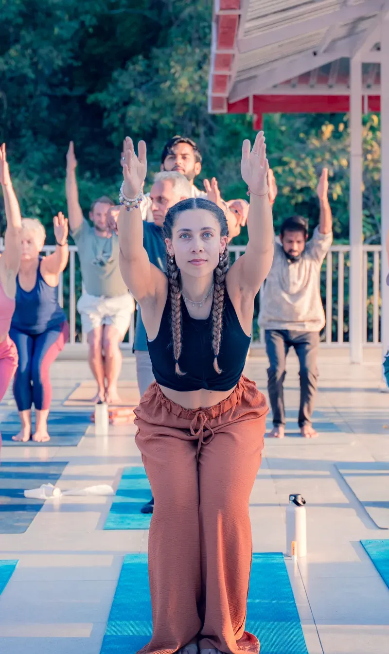 A group practising yoga with raised arms on an open-air terrace