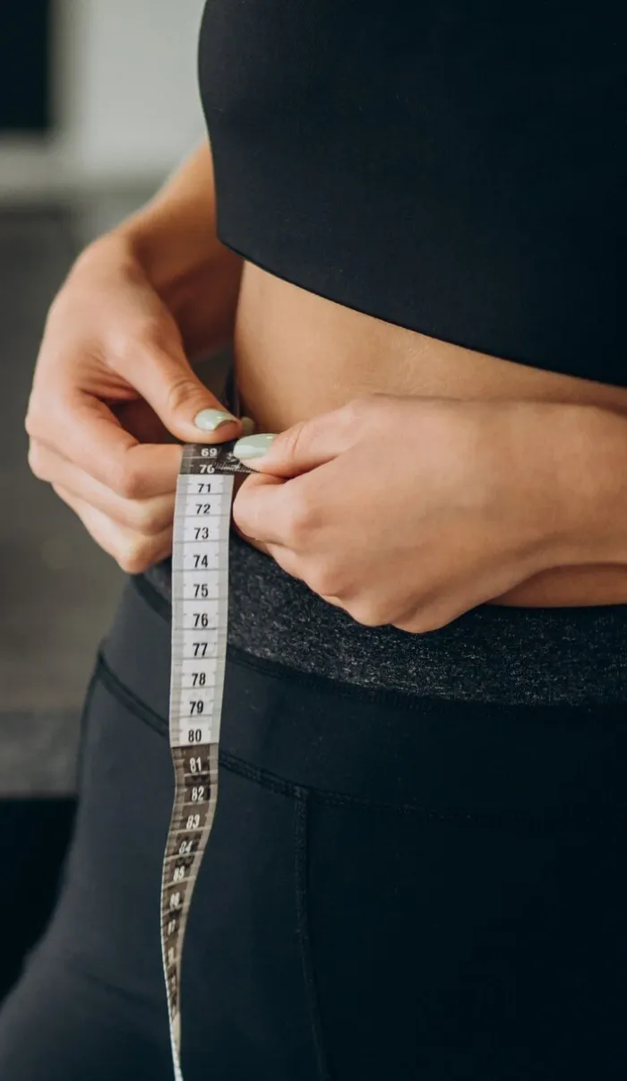 A woman measuring her waist with a tape measure
