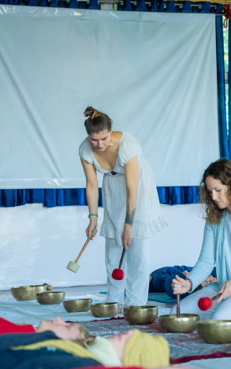 A teacher playing a row of singing bowls around resting students