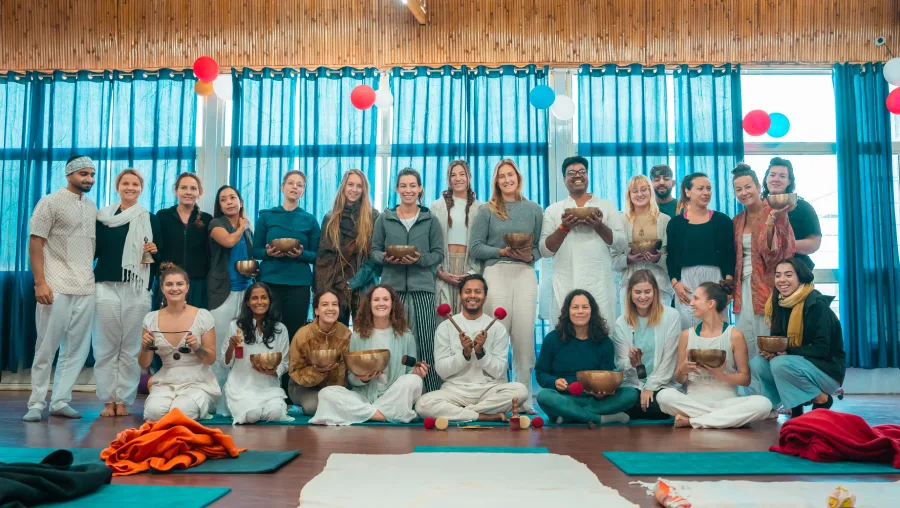 Sound healing graduates holding singing bowls in the yoga hall