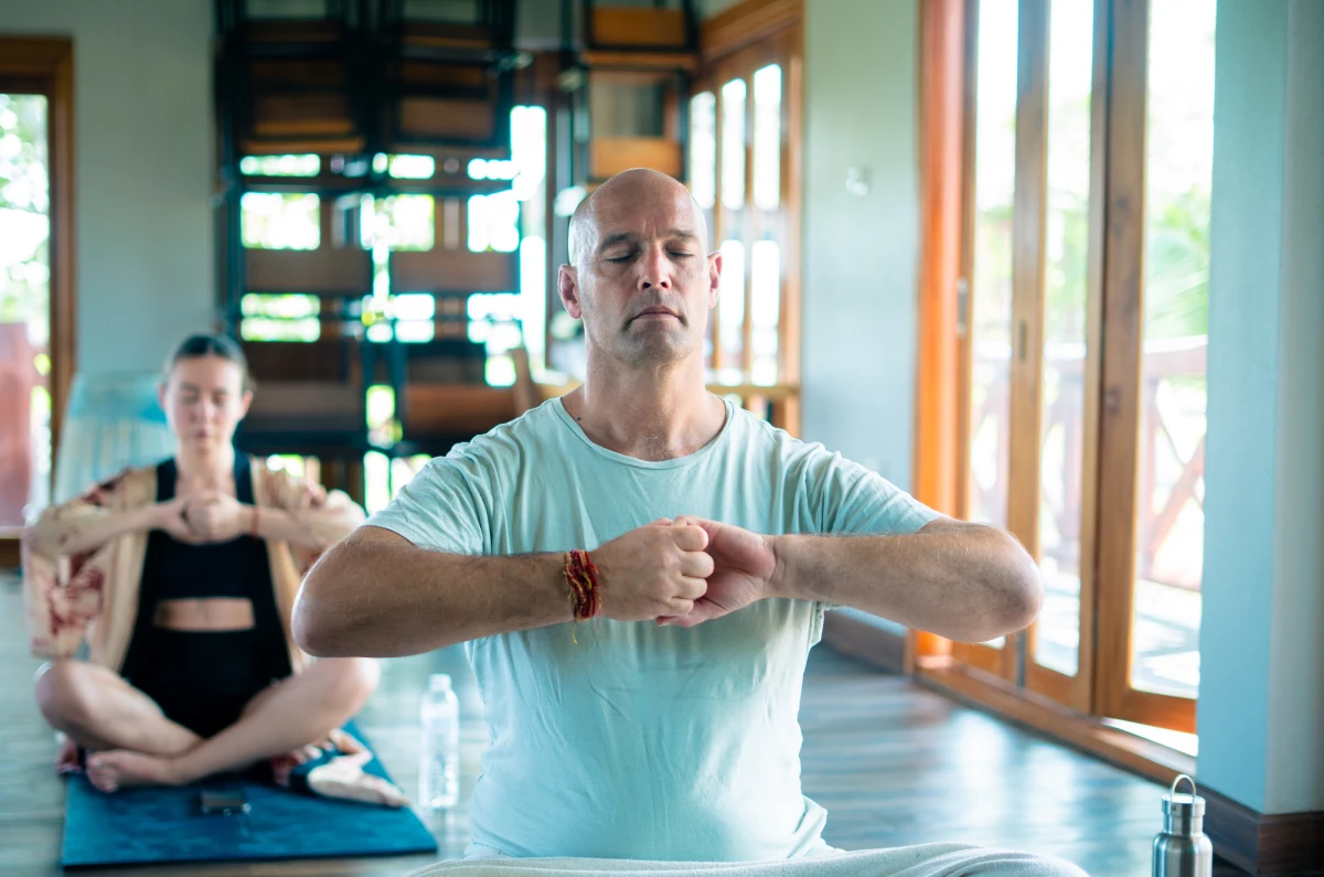 A student practising a kundalini kriya with fists joined at the chest