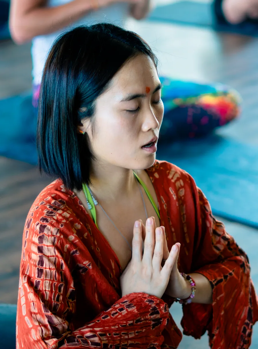 A student chanting with palms joined in prayer during a kundalini class